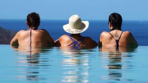 three women in pool looking at ocean