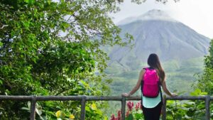 Woman with backpack looking at Arenal Volcano