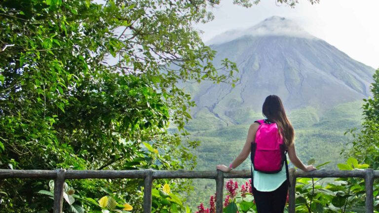 Woman with backpack looking at Arenal Volcano