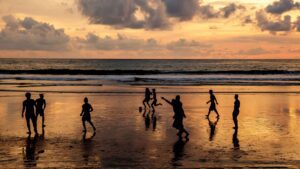 playing soccer on beach at sunset